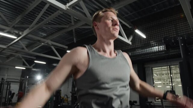 Young Caucasian man performing jumping jacks in gym, focusing on cardiovascular endurance. Footage for fitness center advertisements and healthy lifestyle campaigns