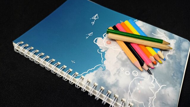 Open blank notebook and sharp colored pencils arranged neatly showcasing vibrant rainbow hues and clean white pages flat lay top view studio shot with bright soft daylight minimal lighting for art edu
