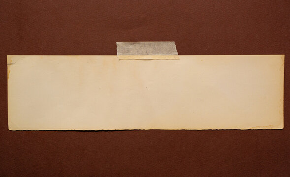 Papel antiguo color crema pegado con cinta adhesiva sobre fondo marr&oacute;n, espacio para texto