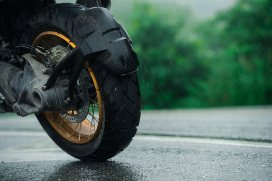 Motorcycle with wet tire on rainy road, showcasing adventure and travel