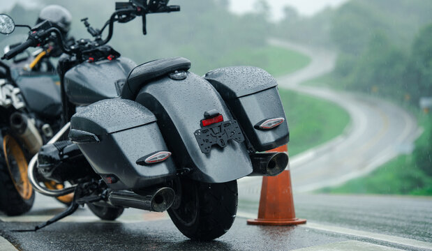 Sleek motorcycle parked on wet road with winding path in background, evoking sense of adventure
