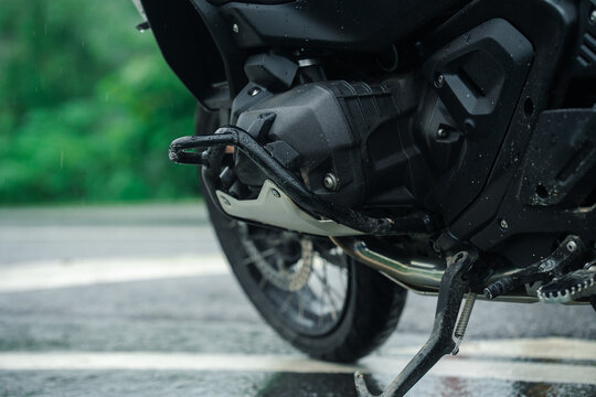 Close up of motorcycle engine with raindrops on wet road, showcasing rugged design and durability