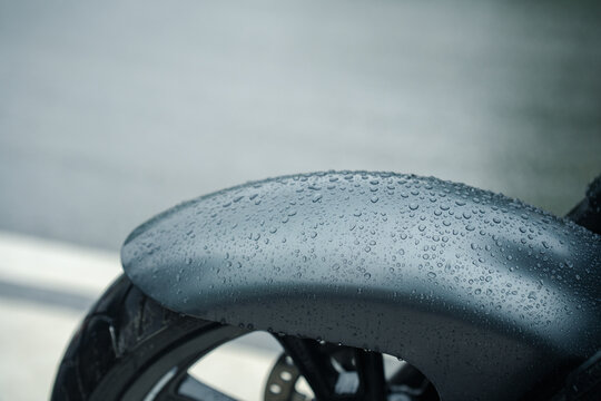 Close up of motorcycle fender with raindrops, showcasing sleek design and wet surface