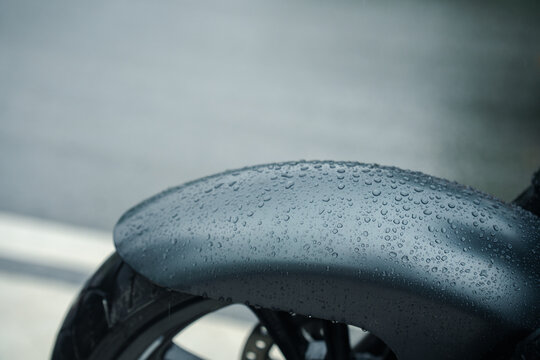 Close up of wet motorcycle fender with raindrops on rainy day