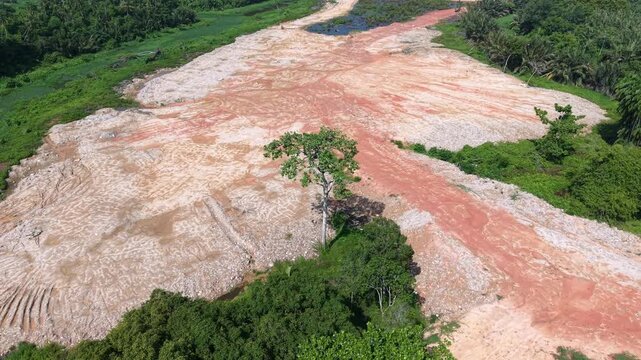 Aerial view of deforested land. Red soil contrasts with green vegetation