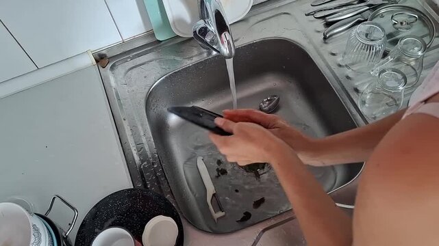 Washing dishes in a kitchen sink with running water and plates being scrubbed