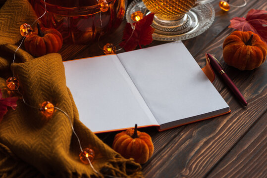 Autumn coziness writing in a blank notebook with tea and pumpkins