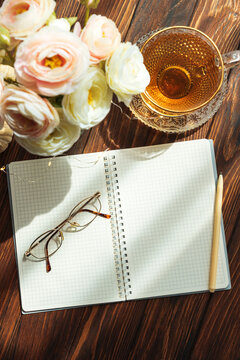 Morning planning notebook with tea, glasses and spring flowers