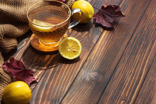 Warm tea with lemon and autumn leaves on wooden table