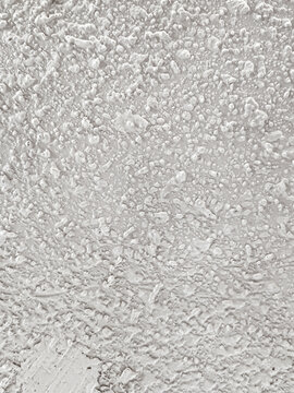 Background of uneven white acoustic wall texture with abstract grain patterns accentuates the modern industrial aesthetic. Close-up of handmade popcorn ceiling has dramatic shadows for decoration.