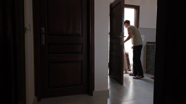 Young man leaving furnished apartment with luggage after temporary stay, housing instability, flexible living, nomadic lifestyle and uncertain future transition concept