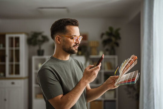 Man using smartphone choosing paint color palette for home renovation