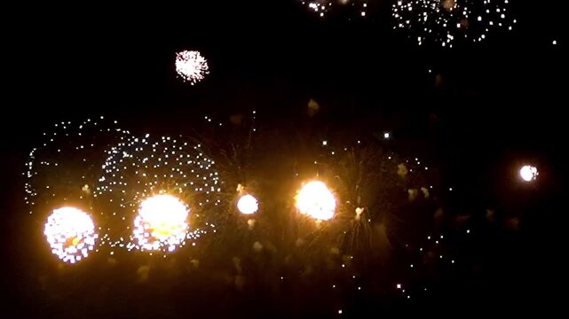 Experience the breathtaking explosion of colors and lights as fireworks light up the night sky, marking a jubilant midnight celebration in the heart of the city.
