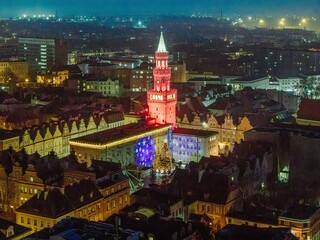 Nocny widok z lotu ptaka na oświetlony Rynek i wieżę ratuszową w Opolu w trakcie świątecznego jarmarku. Świecące iluminacje dodają magii zabytkowemu centrum miasta. © Henryk Niestrój