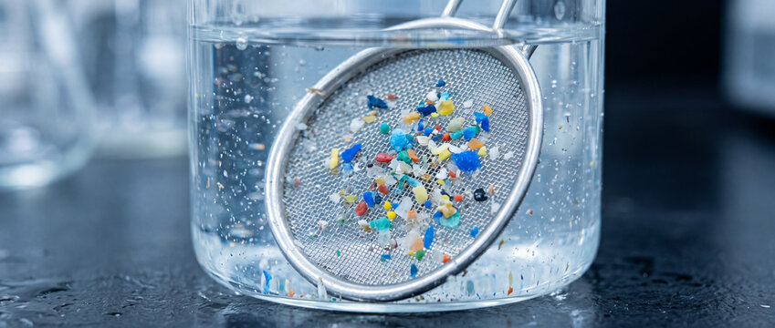 Microplastics filtration in laboratory beaker showing plastic pollution in water sample under analysis