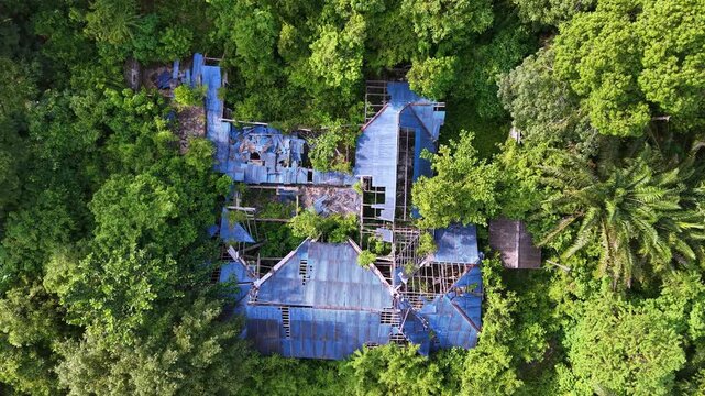 Aerial view captures a dilapidated building with blue corrugated roofs