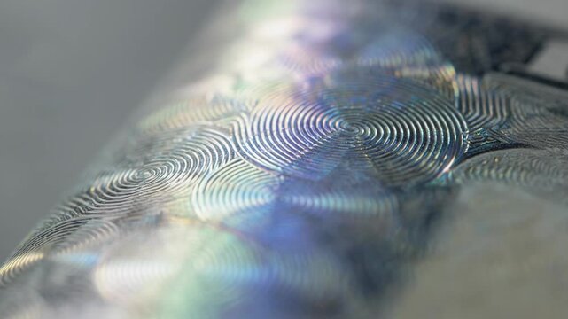 Macro shot of a banknote hologram shimmering under angled light sharply focused on fine details with a softly blurred background.