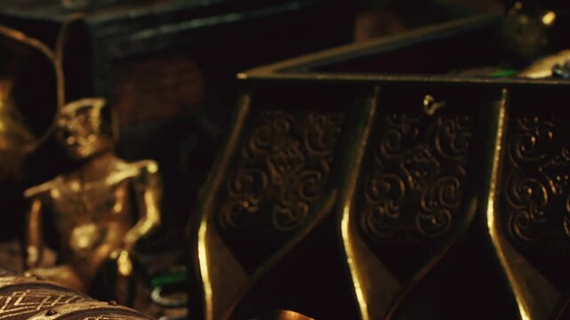 Various artifacts and treasures are arranged on a surface in low light. Objects include gold coins, decorative items, and ancient tools. The scene shows a sense of history and value.