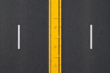 Fototapeta premium Top-down view of a yellow painted median strip dividing a two-lane road.