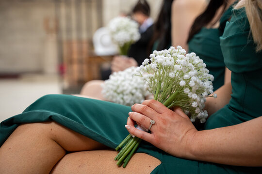 Bridesmaid holding white flower bouquet during wedding ceremony.