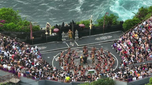 Balinese men performing the traditional Kecak fire dance for a large audience on a cliffside stage overlooking the ocean, showcasing rich Indonesian culture and spirituality. Uluwatu Temple, Bali