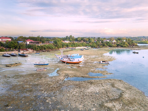 Cool afternoon, the sun beginning to tilt toward the west, the tide going out, several large wooden boats seen undergoing repairs before continuing their journey 