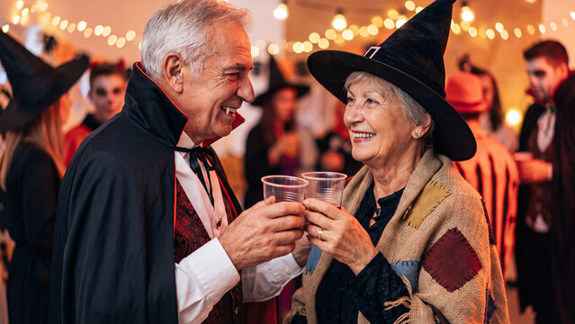 senior couple in halloween spooky night dance party in wearing halloween spooky costume enjoying drink