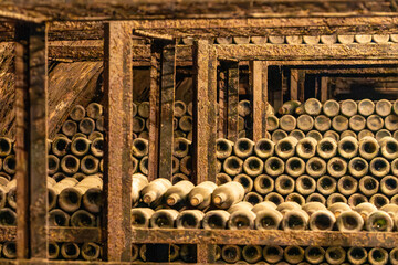 Dust and Rust. Ancient dust-covered wine bottles aging on rusty racks in a dark cellar. © HansMorten