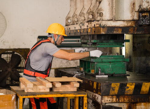 Machine operator positioning metal component inside open press die