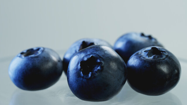 Macro close-up shot of fresh blueberries on pastel gray background with copy space. Juicy organic berries for healthy food blog, recipe cover, web banner, minimalist menu, and social media template.