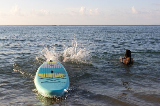 splash, female friends jump to water from SUP, summer fun on beach