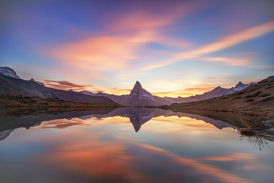 Pastel dawn sky mirrored in alpine lake beneath the Matterhorn