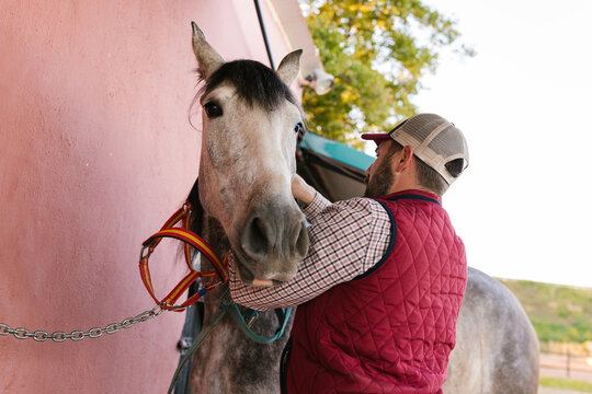 Man preparing horse for riding outdoors
