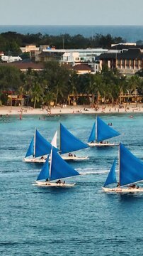 Sunset paraw sailing boats over the blue sea and powdery white sand beach in Boracay Island. Philippines. Vertical view.