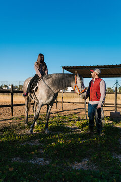 Girl learning to ride horse with instructor