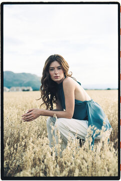 Woman crouching in wheat field 