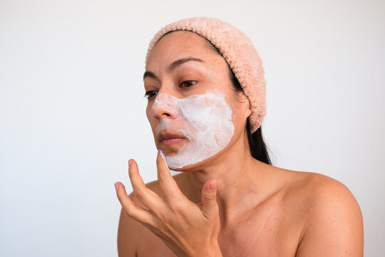 Woman Applying Face Mask in Home Setting During Daylight Hours