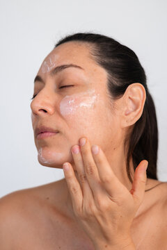 Woman Applying Skincare Product on Her Face Indoors