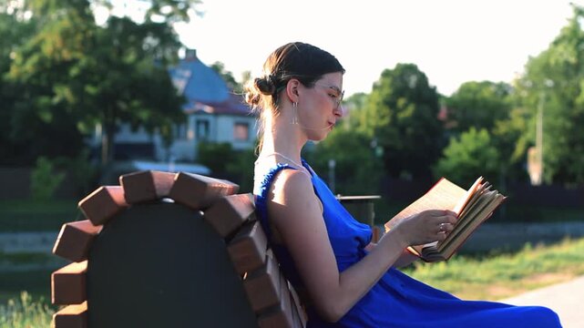 Girl with book on park bench. Conscious gadget break. Harmony with nature and literature. Slow living at its best. Seasonal ritual of summer reading outdoors. Book lovers day