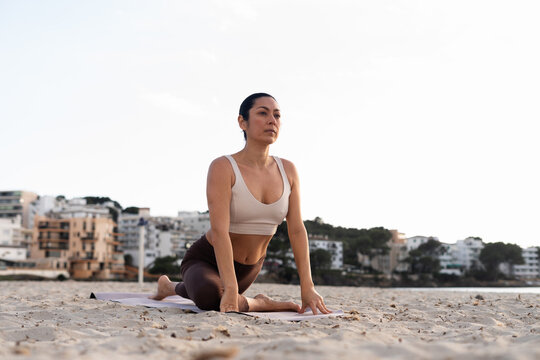 Woman Practicing Yoga at Beach During Sunset