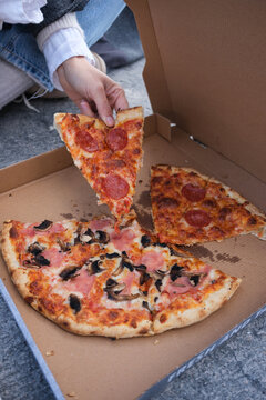 Enjoying Pizza Slices on a Sidewalk With Friends