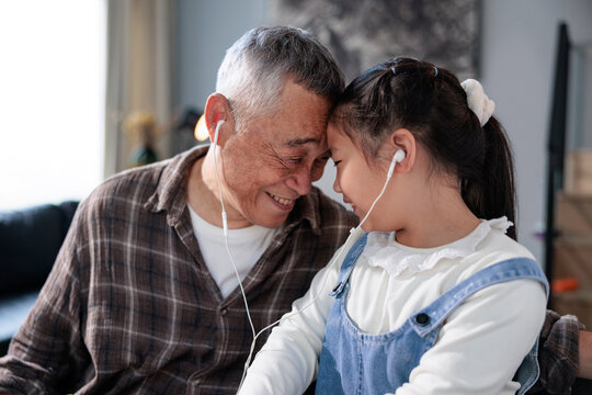 Grandfather and granddaughter listening to music together