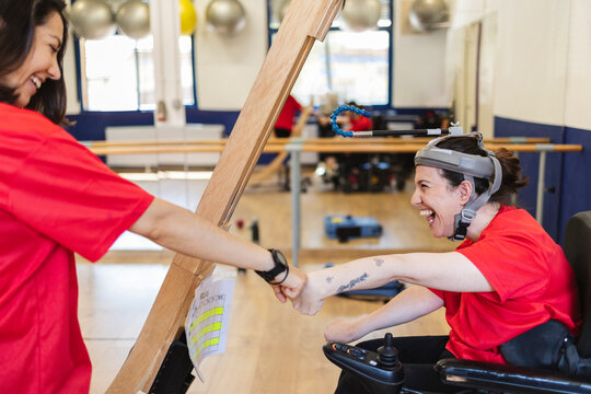 Therapist celebrating progress with disabled woman using