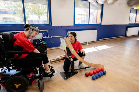 Young woman with physical disability playing boccia with instructor