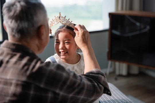 Grandparent crowns smiling girl with tiara.