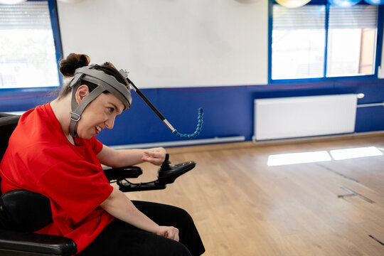 Woman with assistive technology head pointer using electric wheelchair