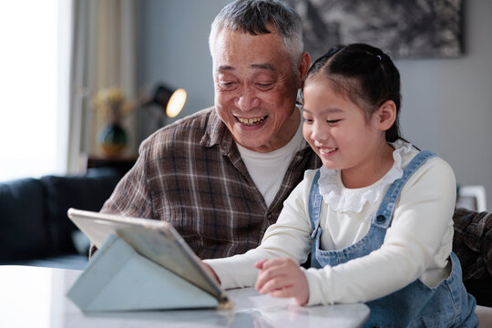 Grandfather and granddaughter share a happy moment with a tablet.
