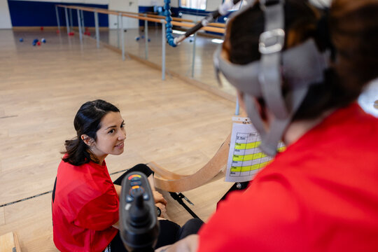 Coach supporting boccia athlete playing adaptive sport