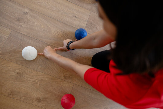 Person playing bocce game on wooden floor
