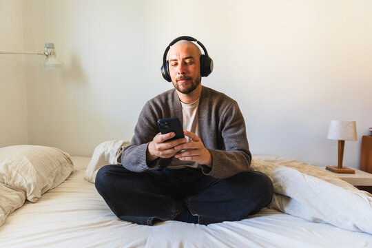 Man Sitting Cross Legged with Phone on Bed